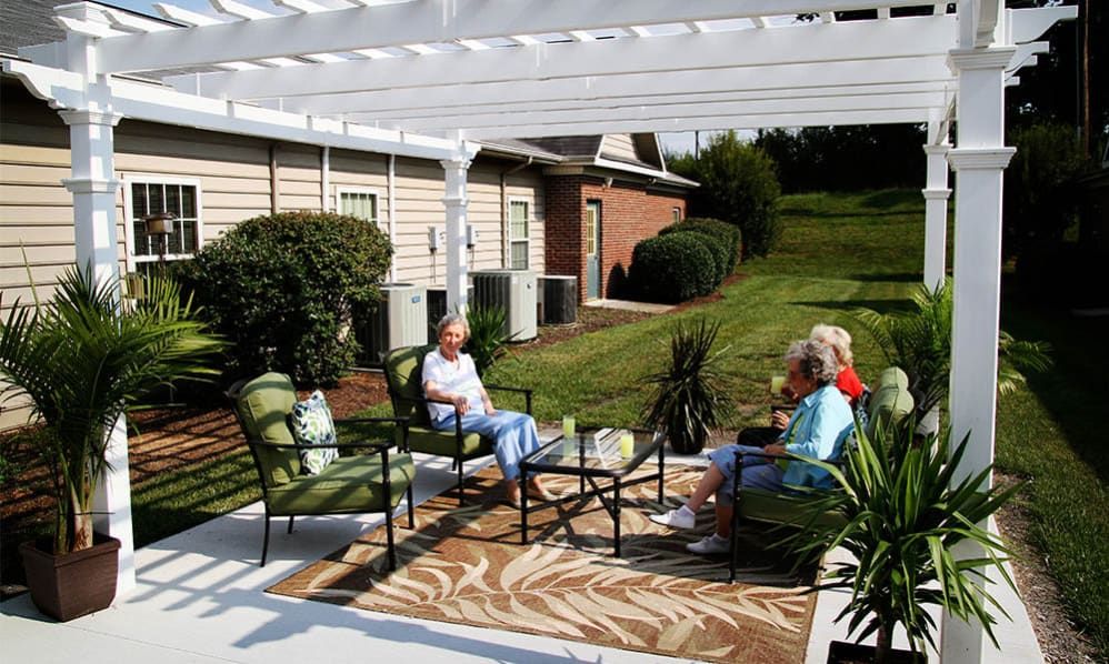 A group of people sitting and relaxing under a pergola on a patio with outdoor furniture.