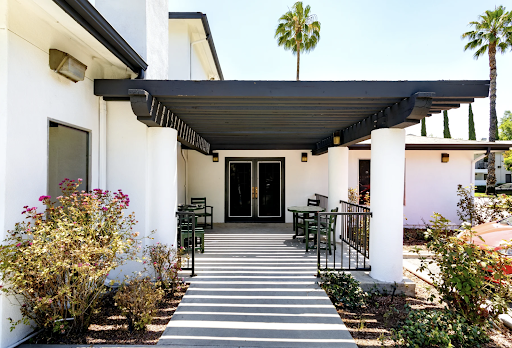 A welcoming entrance featuring a modern design with shaded seating and lush landscaping.
