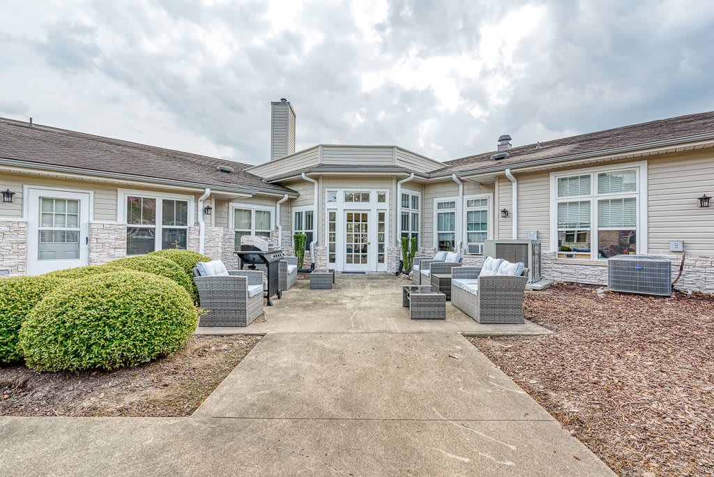 A spacious backyard patio with modern outdoor furniture and a view of a large house.
