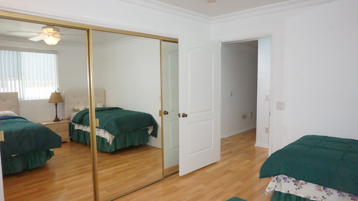 A modern bedroom with mirrored closet doors and green bedding on a bed.