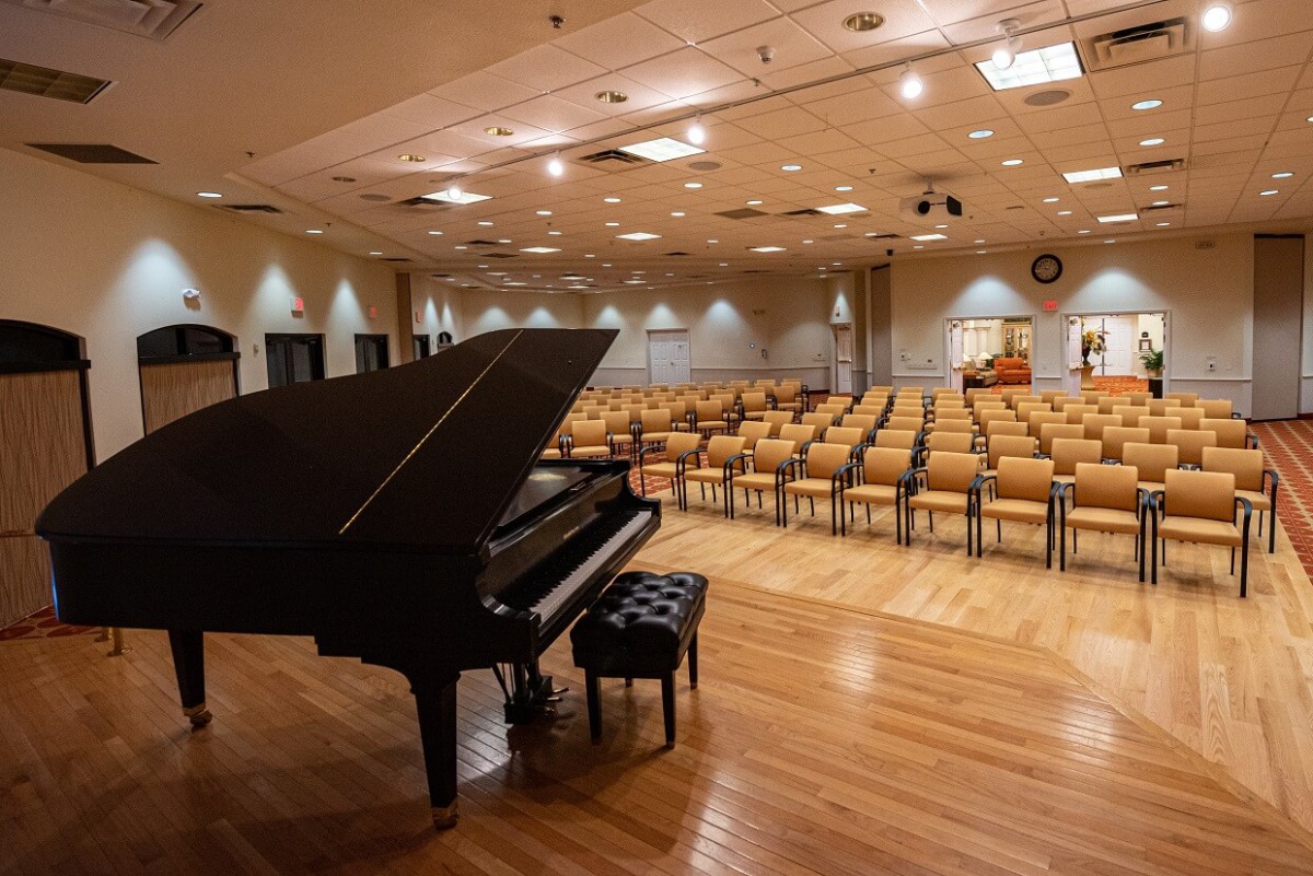 An empty concert hall with a grand piano on stage and rows of seats awaiting an audience.