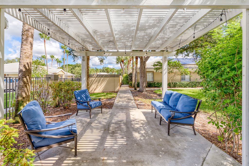 A cozy outdoor patio with blue-cushioned seating under a pergola.