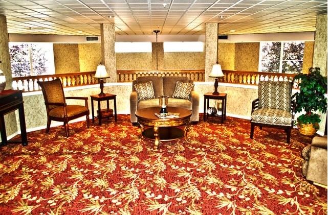 A hotel lobby with a seating area, featuring patterned carpet and elegant furniture.