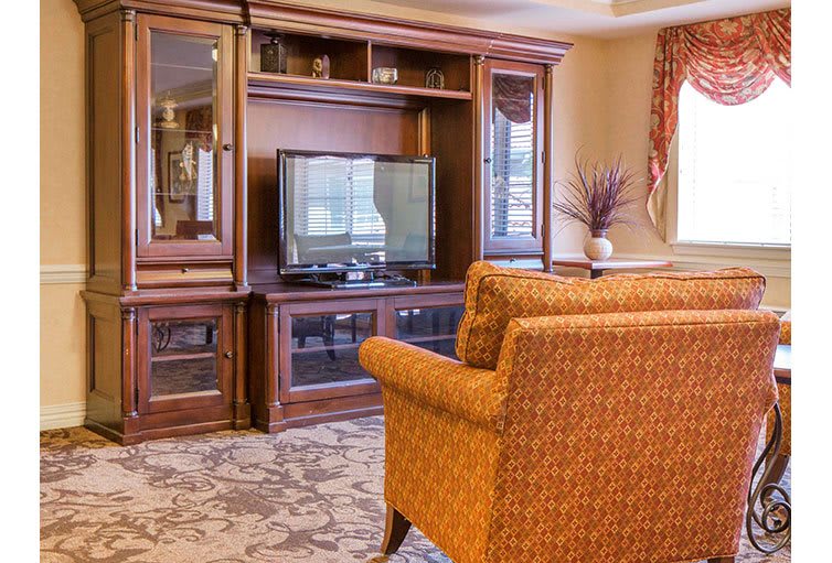 A cozy living room with a wooden entertainment center and comfortable chairs.