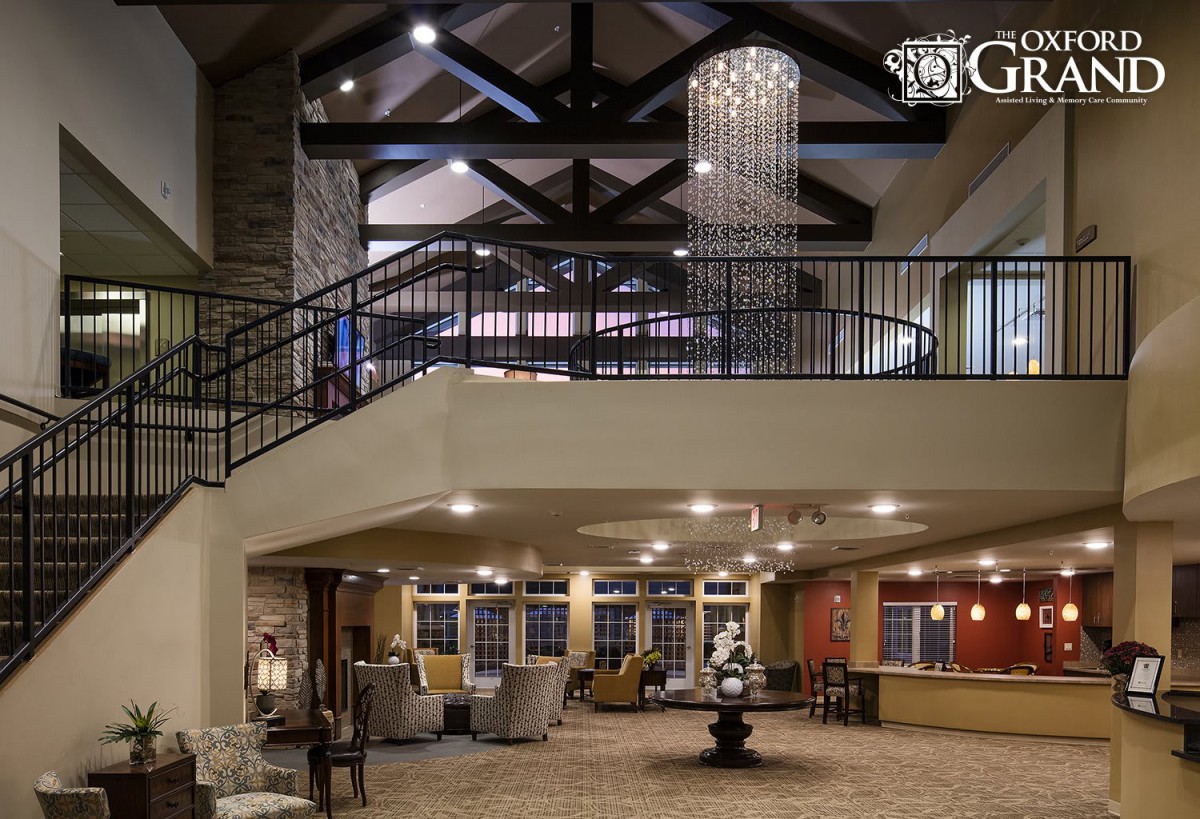 A spacious and modern lobby interior with high ceilings, a large chandelier, and comfortable seating.
