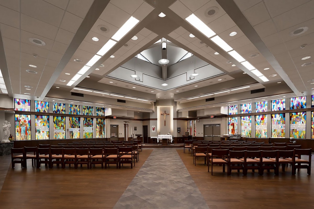 Interior view of a modern church featuring stained glass windows and an altar.