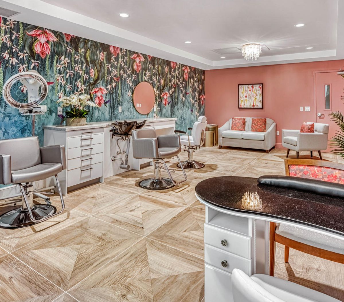 A stylish salon interior featuring floral wallpaper, comfortable seating, and modern furnishings.