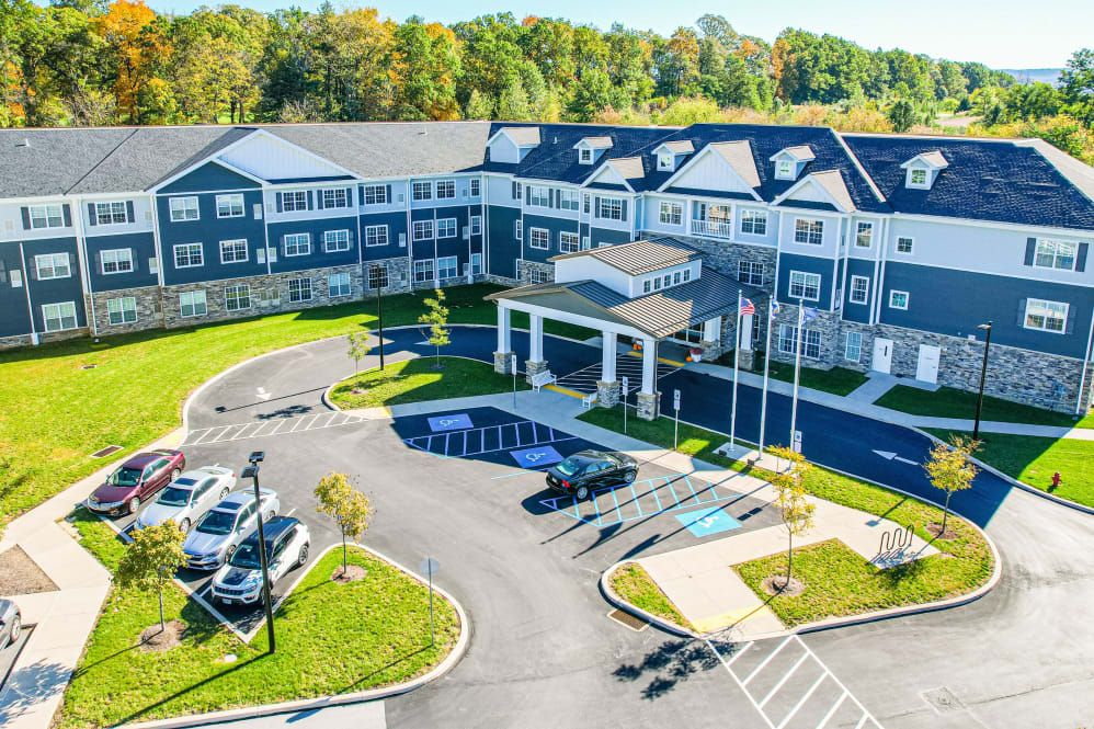Aerial view of a large residential or commercial building with a parking lot and landscaped grounds.