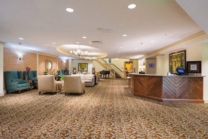 A spacious hotel lobby featuring a reception desk, comfortable seating, and elegant lighting.
