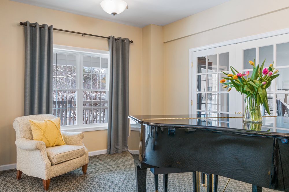 A cozy living room with a grand piano and a comfortable chair by the window.