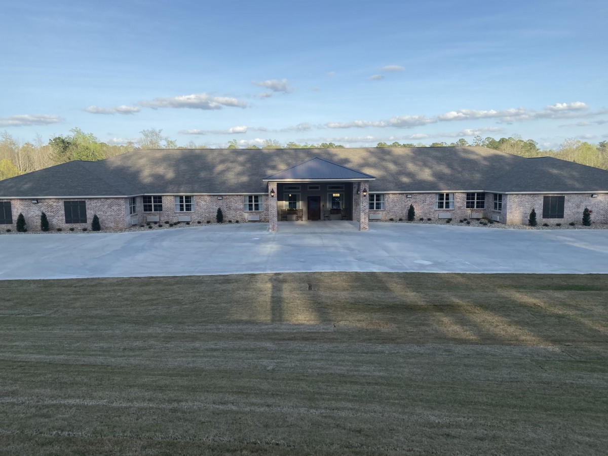 A large house with a spacious driveway under a clear sky.