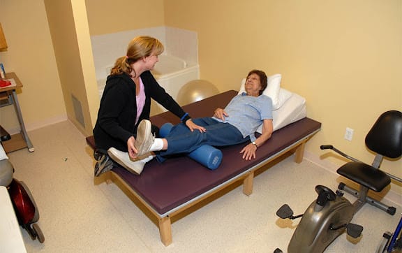A therapist assists a patient with therapeutic exercises during a physical therapy session.