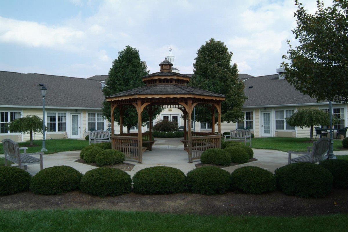 A charming gazebo surrounded by manicured bushes and trees in a landscaped garden.