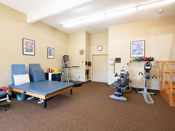 A well-equipped physical therapy room with exercise machines and rehabilitation equipment.
