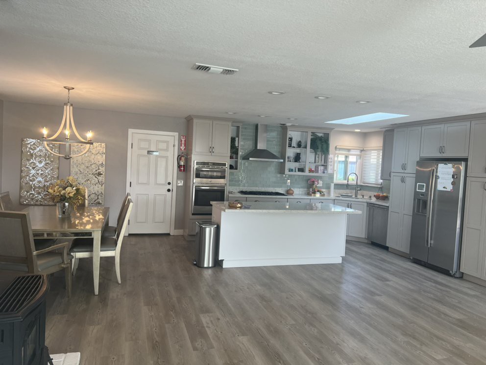 A modern open-plan kitchen and dining area with sleek white cabinetry and hardwood flooring.