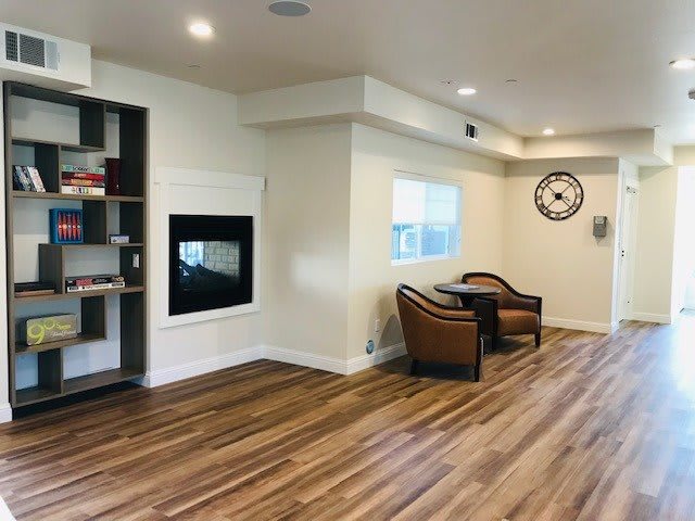 A modern living room with wooden flooring, featuring a fireplace and a cozy seating area.