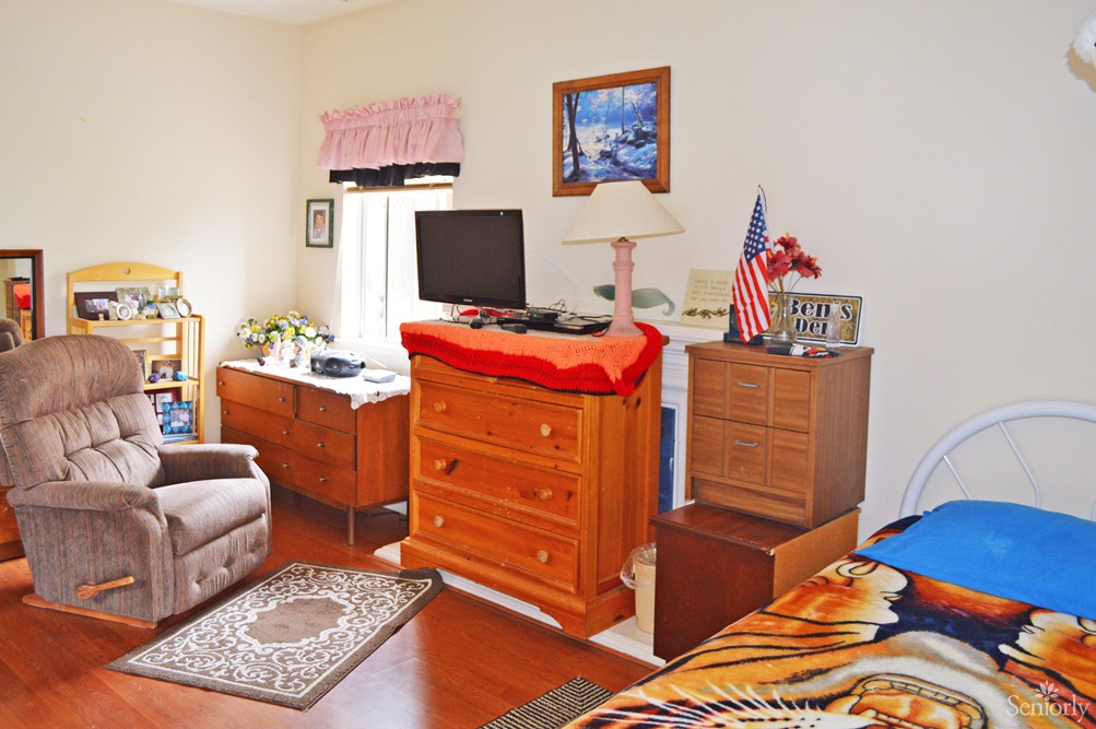 A cozy bedroom with wooden furniture, including a dresser and a TV, alongside decorative items and an American flag.