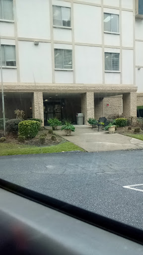 A view of the entrance to a building with landscaped greenery and a pathway.