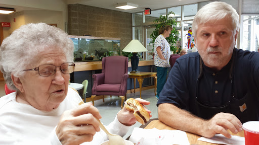 Two individuals enjoying a meal and engaging in conversation in a communal dining area.