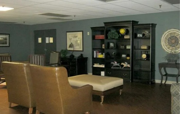 A cozy office lounge area with a seating arrangement and bookshelves.