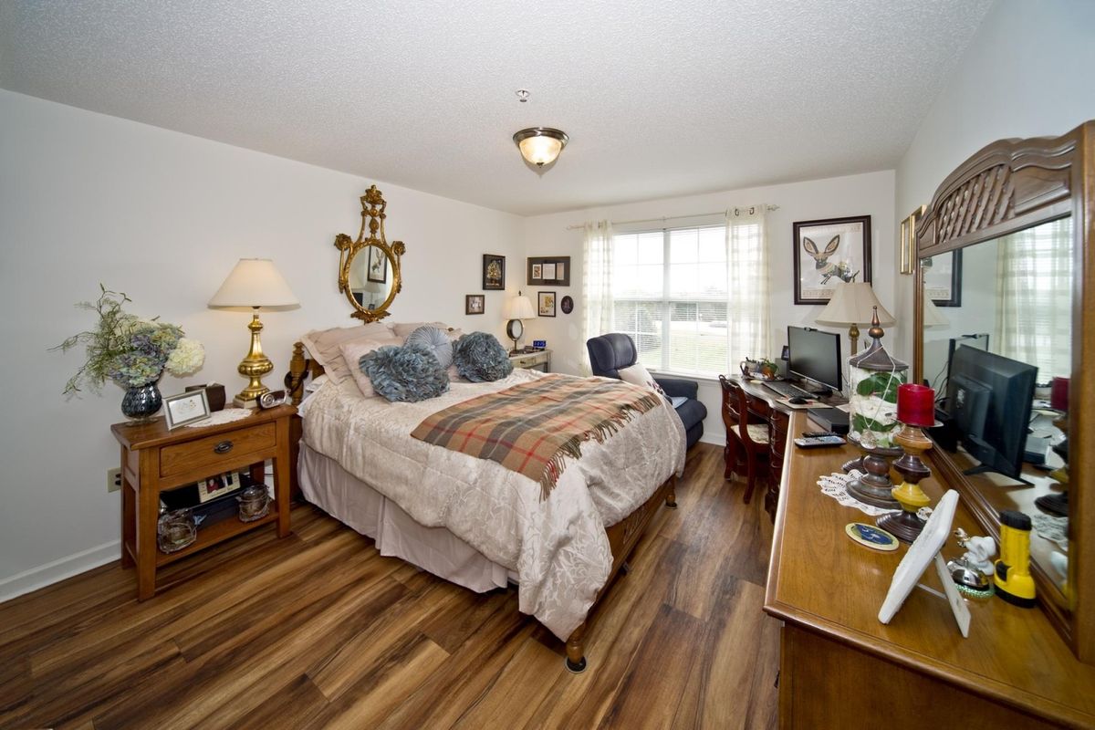 Cozy bedroom with a large bed, wooden flooring, and various decorative elements.