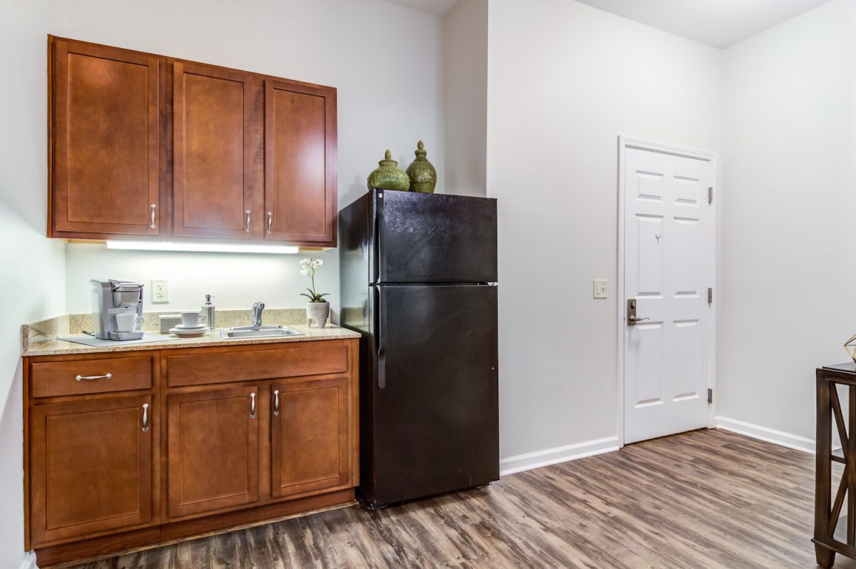 A compact kitchen area with wooden cabinets and a black refrigerator.
