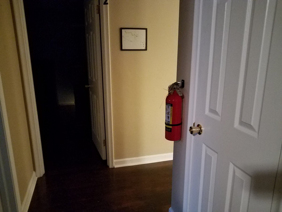 A dimly lit hallway with a fire extinguisher mounted next to an open door.