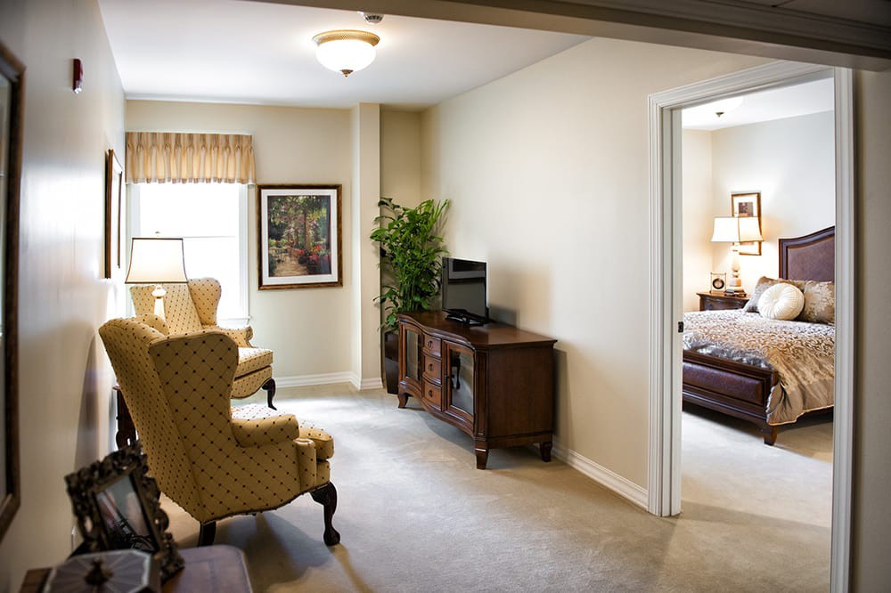 A cozy living room with elegant armchairs, a console table with a TV, and ample natural light.