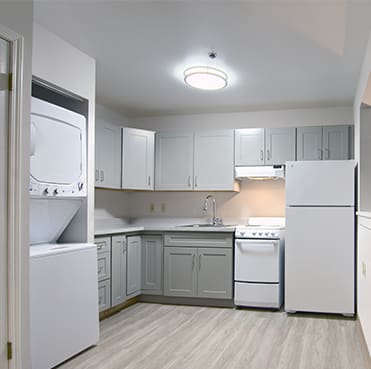 A modern kitchen with integrated laundry appliances and neutral tones.
