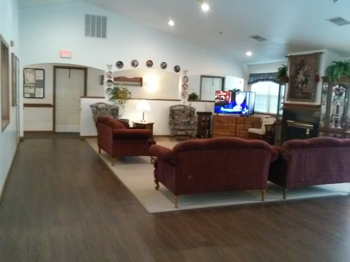 A spacious living room with plush sofas, a television, and wooden flooring.