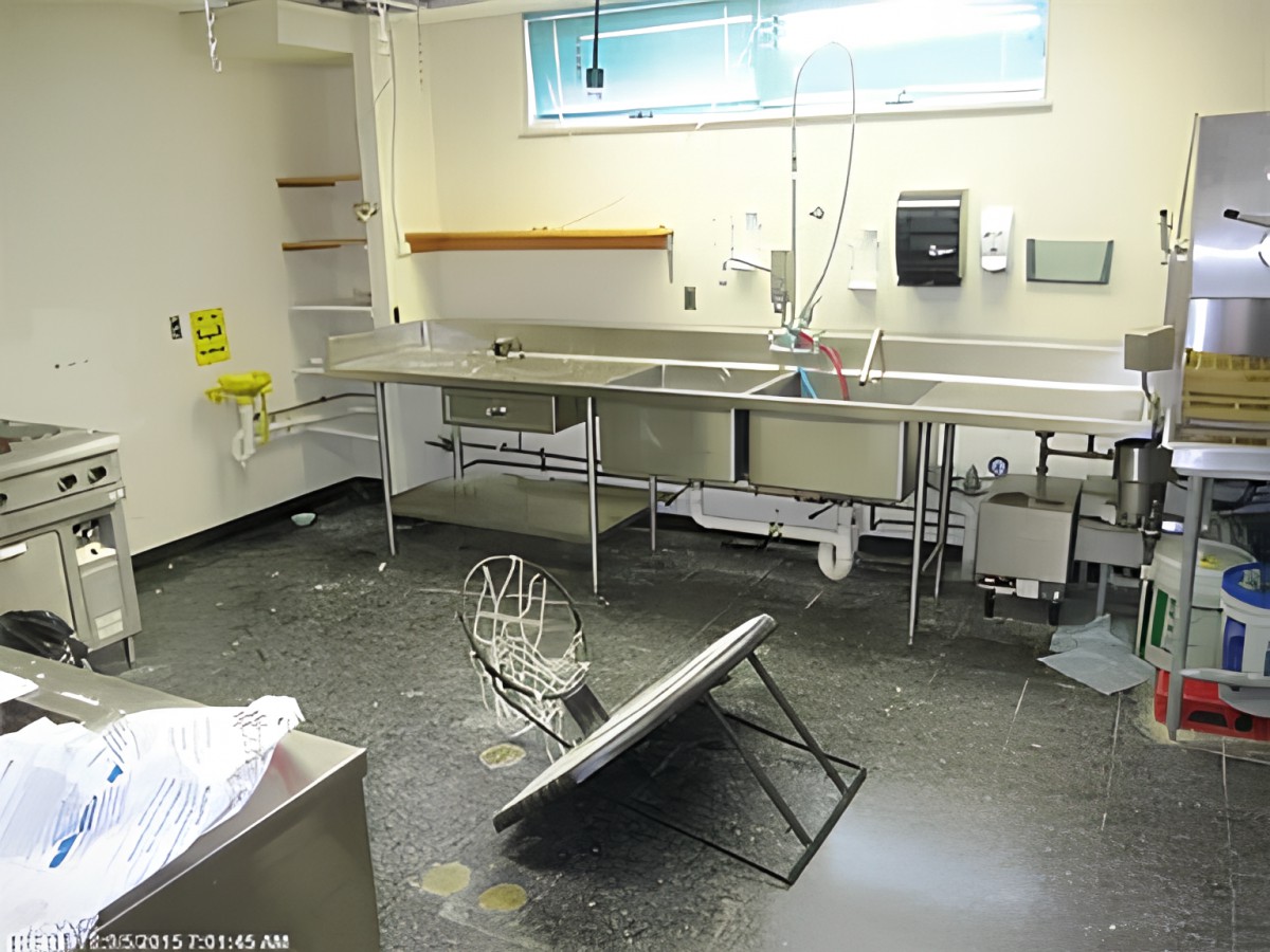 A disorganized laboratory space with a tipped over chair and multiple sinks.