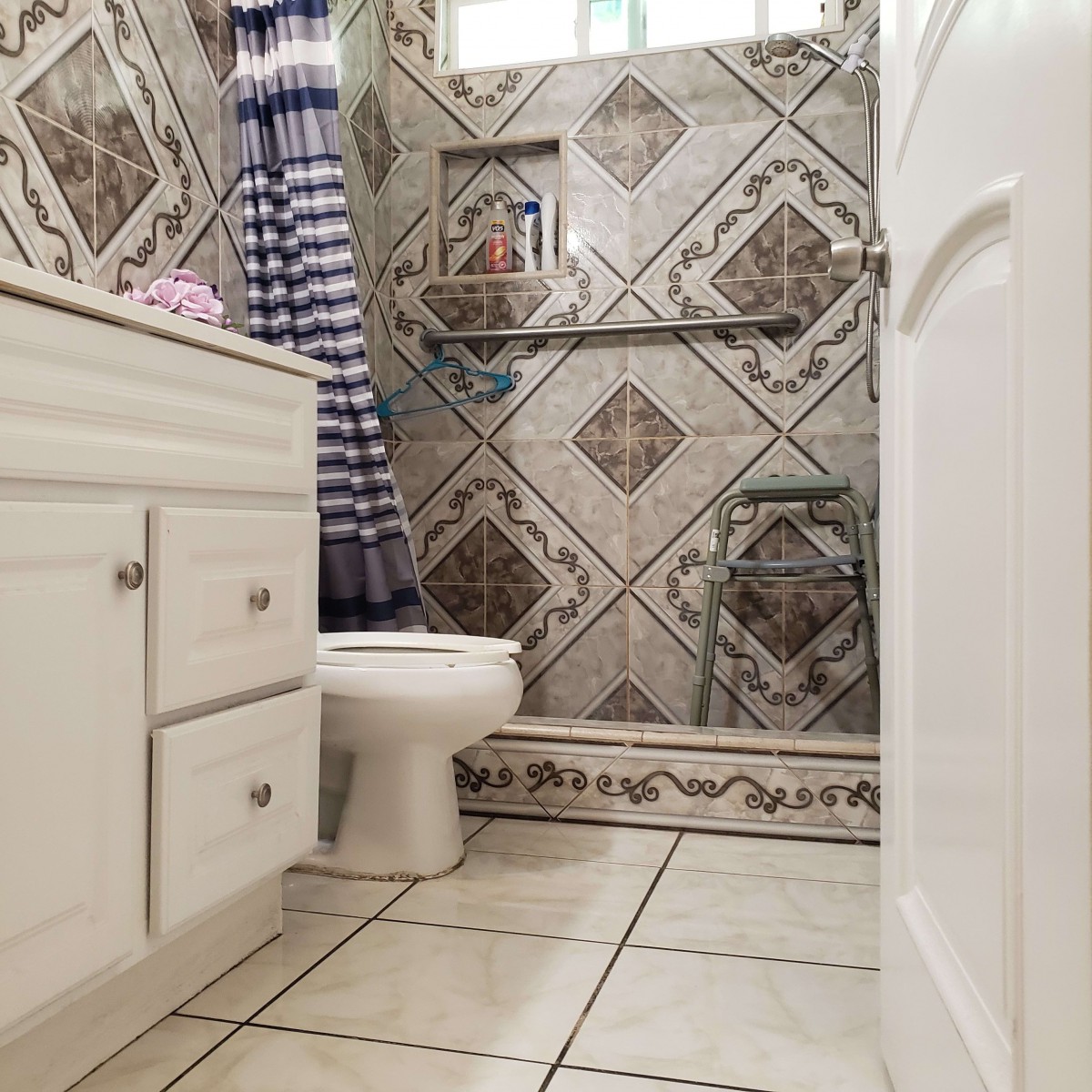 A bathroom with decorative tile walls and a blue-striped shower curtain.