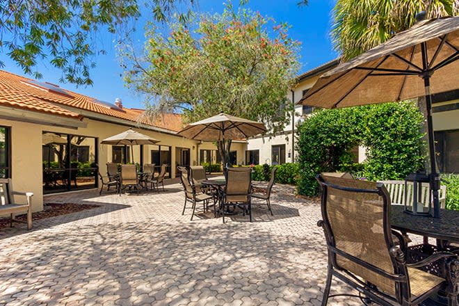 A charming patio area with tables, chairs, and umbrellas under a sunny sky.
