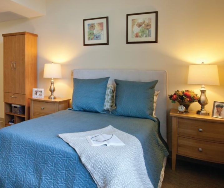 A cozy bedroom with a neatly made bed, flanked by bedside tables and warm lighting.