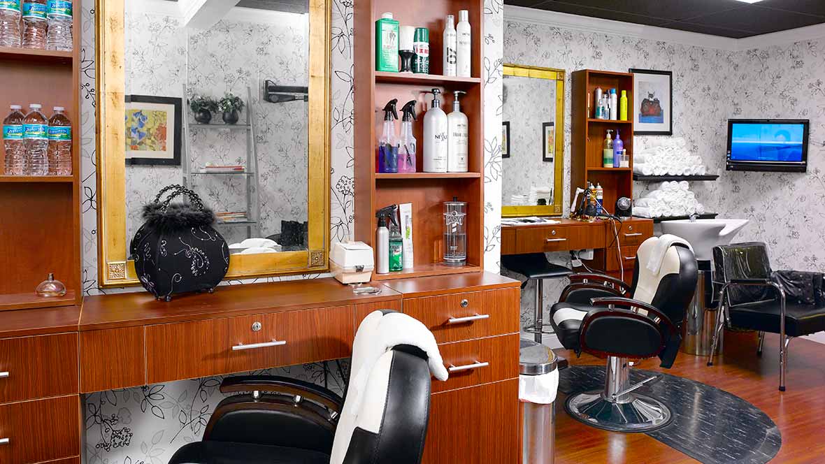 A stylish and modern barber shop interior with mirrors, chairs, and shelves stocked with hair products.
