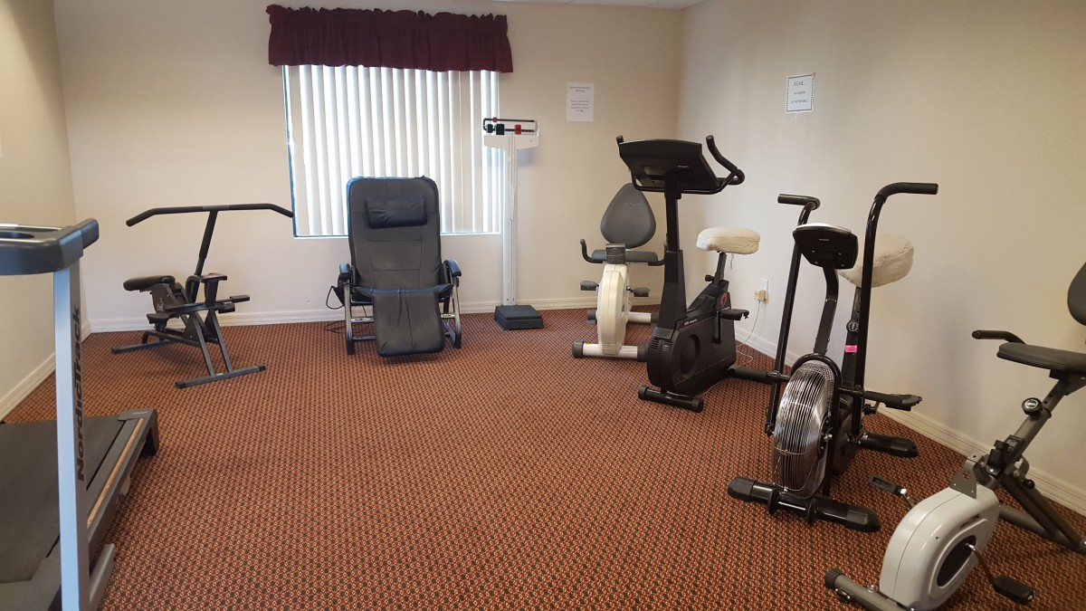 A small gym with various exercise equipment including stationary bikes and a scale.