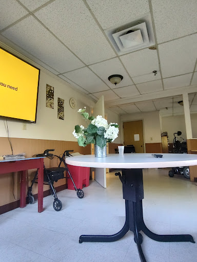 A spacious interior room featuring a table with flowers, a television on the wall, and wheelchair accessibility.