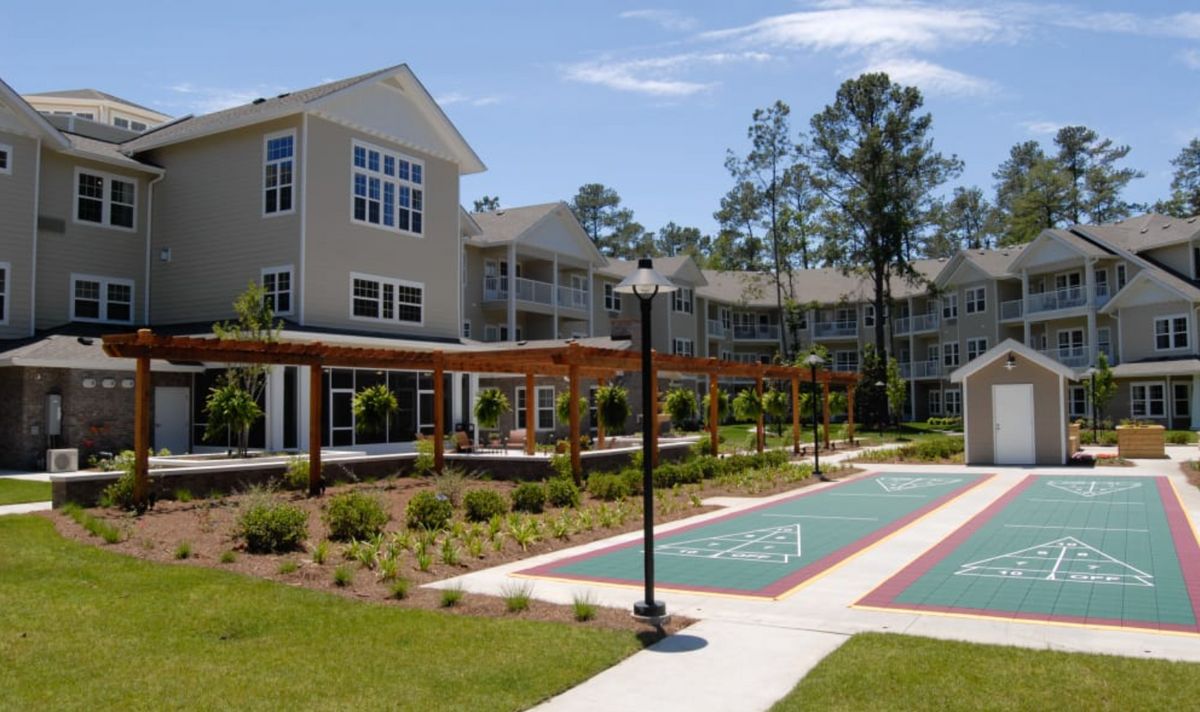 A modern apartment complex with well-maintained landscaping and an outdoor court.