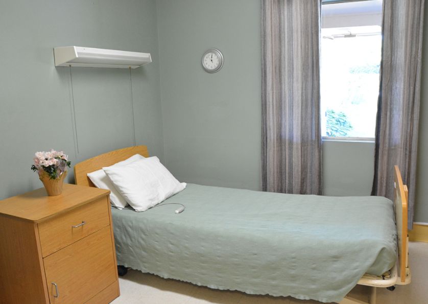 A minimalist hospital room with a single bed and a window, conveying a sense of cleanliness and simplicity.