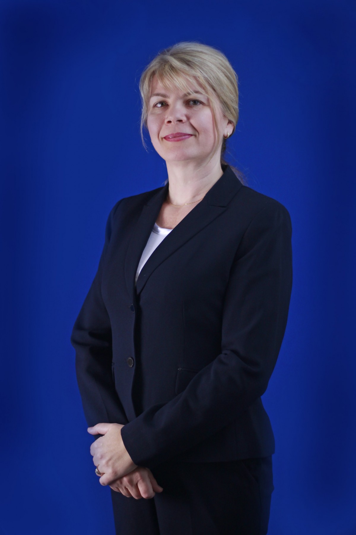 A professional portrait of a woman in business attire with a blue background.