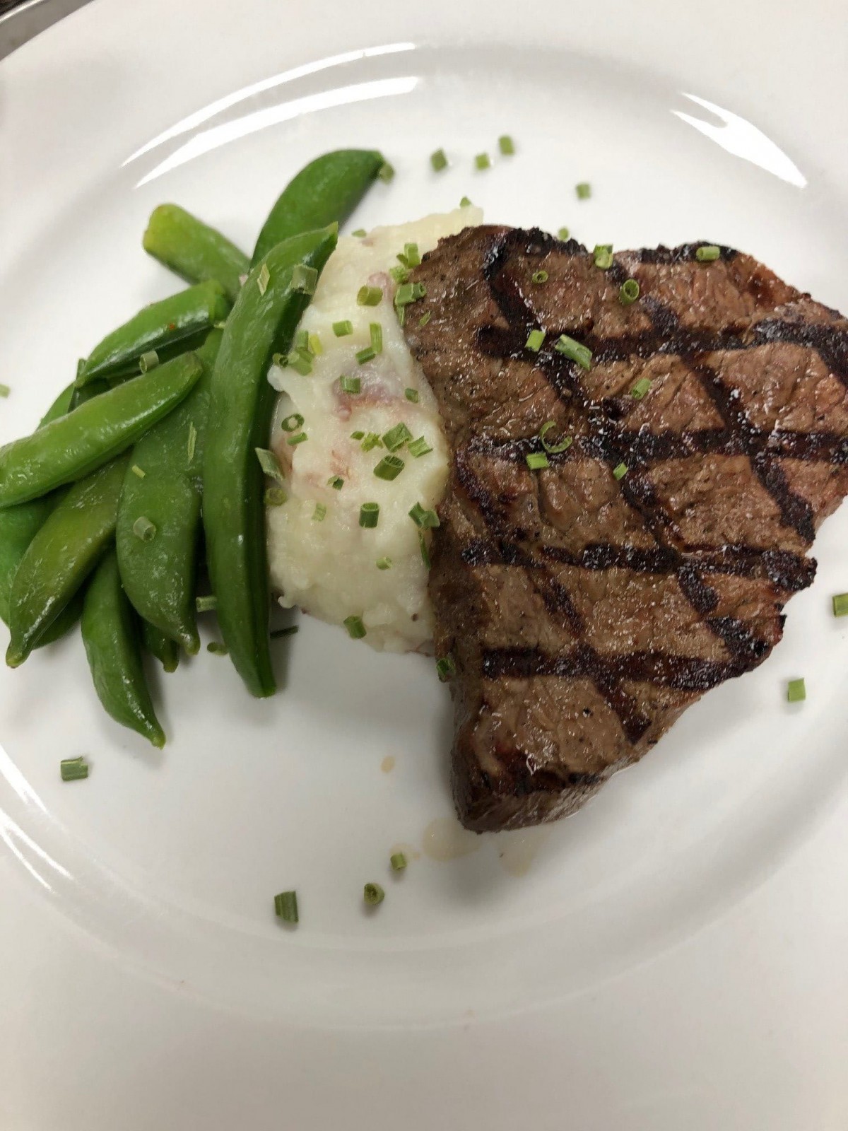 A grilled steak served with mashed potatoes and green beans.