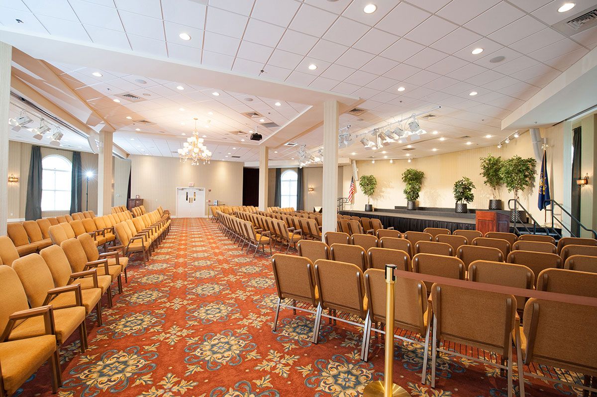 A spacious conference room with rows of chairs facing a stage, ready for an event or presentation.