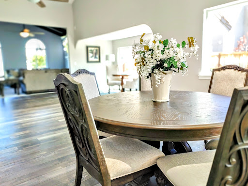 A cozy dining area featuring a wooden table adorned with a vase of fresh flowers, set in a bright and inviting home.