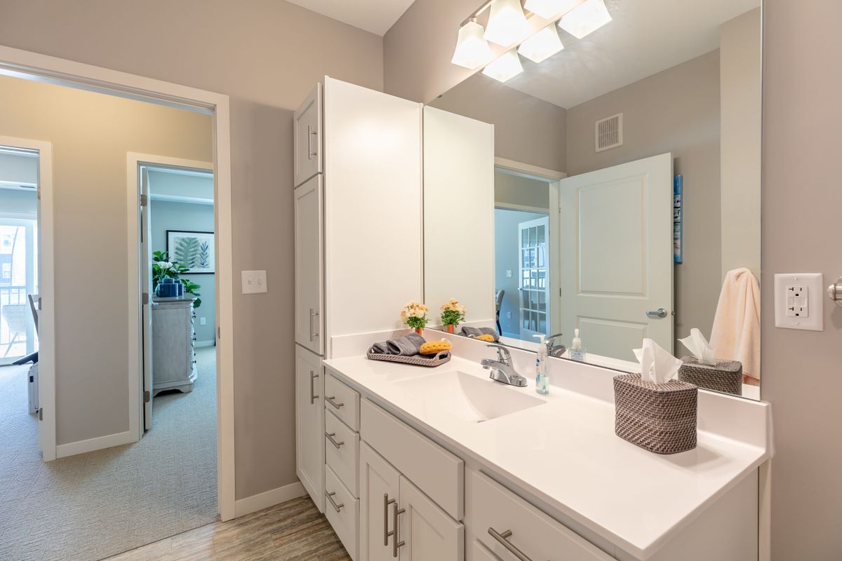 A modern bathroom featuring a sleek vanity with a large mirror and bright lighting.