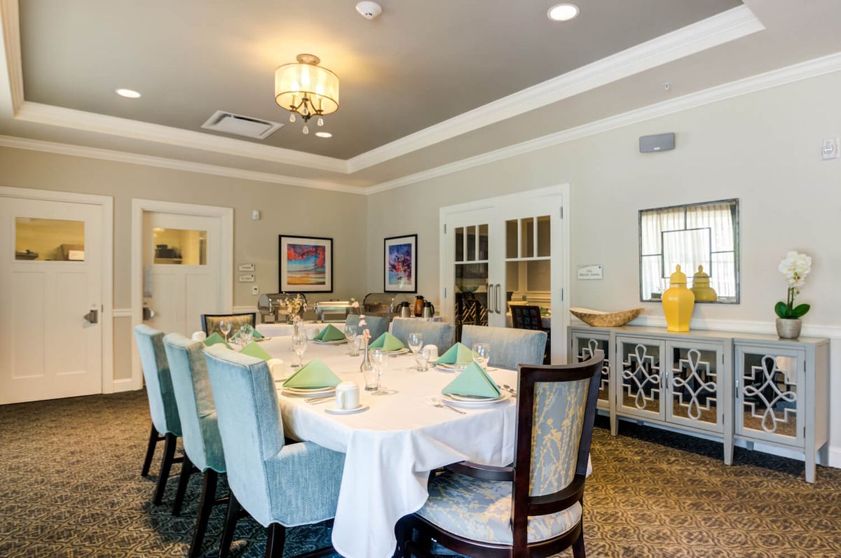 An elegantly set dining room with a large table and chairs, decorated with a chandelier and tasteful decor.