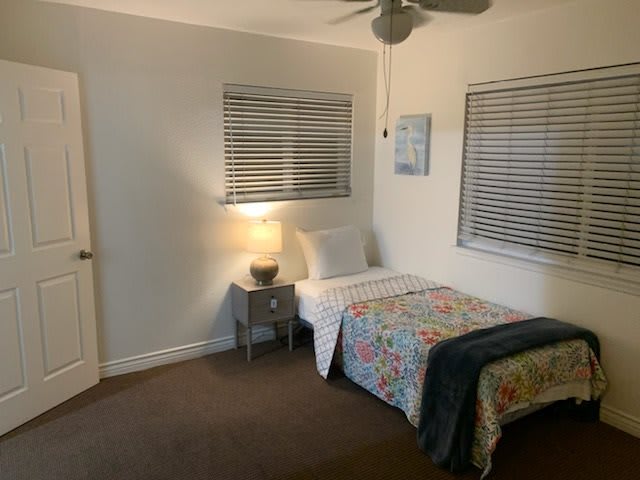 A cozy bedroom with a single bed and nightstand under warm lighting.