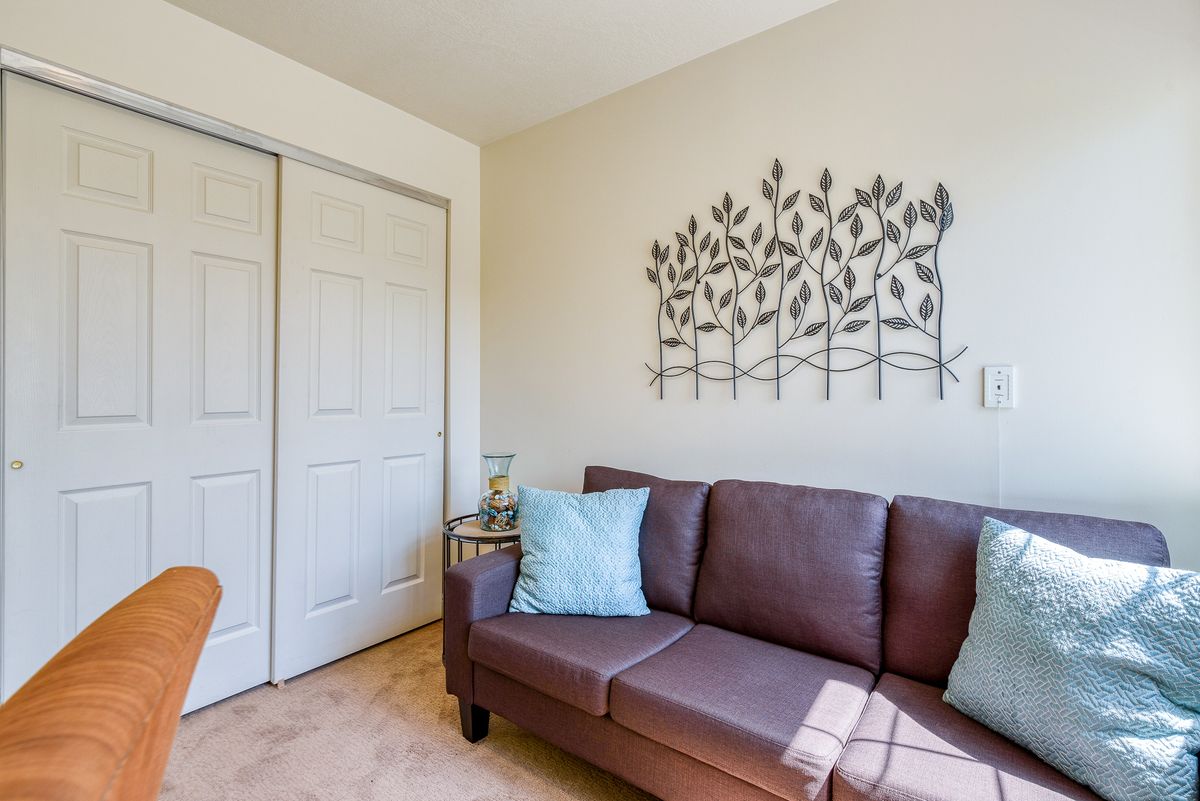 A cozy living room with a brown sofa, decorative pillows, and metal wall art.