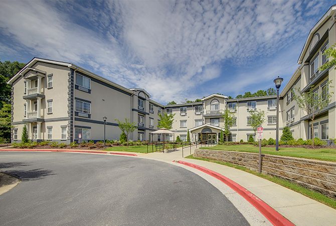 A modern residential apartment complex with a well-maintained exterior under a cloudy sky.