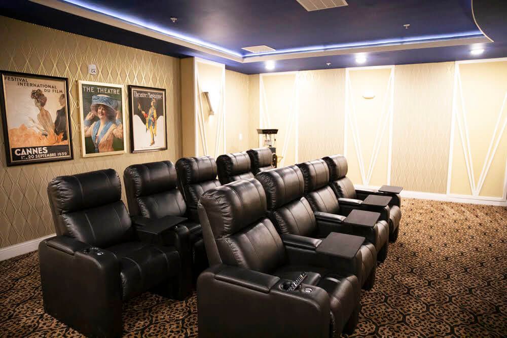 A cozy home theater setup with reclining chairs and movie posters on the wall.