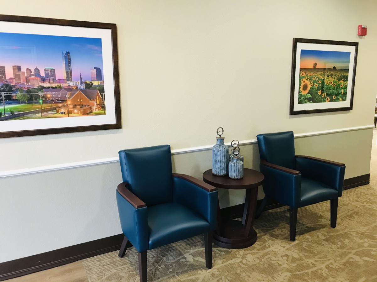 A cozy waiting room with blue chairs and framed pictures on the wall.